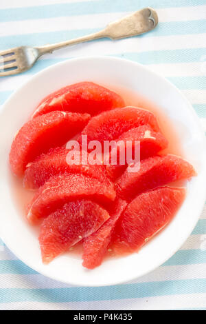Red grapefruit pieces, segments on white plate Stock Photo