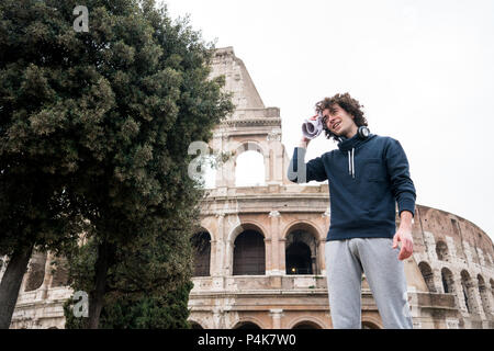 Handsome young sportsman relaxing after training wiping sweat with a towel in front of Colosseum in Rome Stock Photo