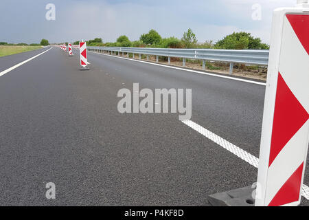 New asphalt lane of a highway divided by a many roadwork marks signs. Stock Photo