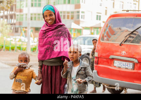 Addis Ababa, Addis Ababa, Ethiopia, January 27, 2014, Mother and two children holding hands on a quiet city street while enjoying a snack, January 27, Stock Photo