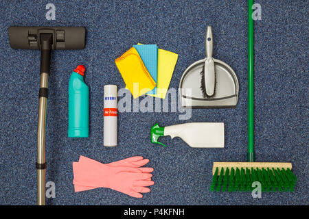A flat lay arrangement of cleaning equipment on a blue office carpat background. Stock Photo