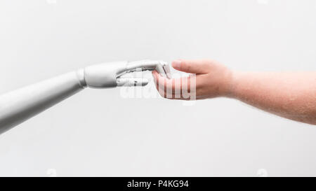 A robot reaches out and reaches for a human hand. The fingers touch and hook themselves. Like a first, tentative body contact. Isolated in front of wh Stock Photo