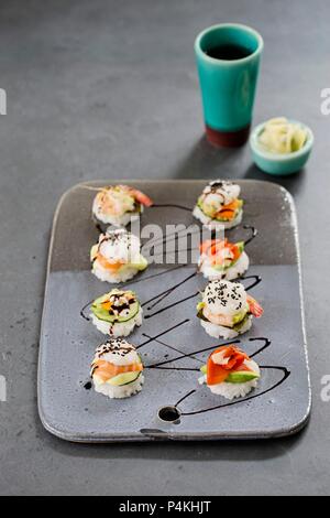 Eight mini sushi burgers on a ceramic plate with smoked and fresh salmon, surimi and shrimp Stock Photo