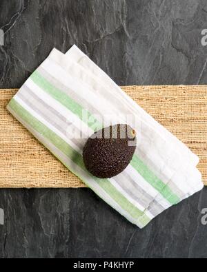 A whole avocado on a fabric napkin (seen from above) Stock Photo
