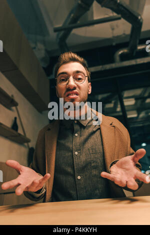 portrait of bully man gesturing and looking at camera in cafe Stock Photo