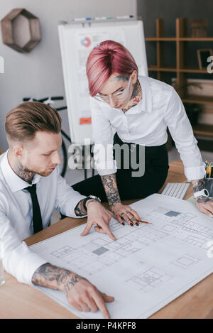 concentrated young business people working with blueprint in office Stock Photo