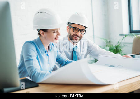 smiling architects working with building plan at office Stock Photo