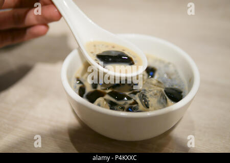 Grass jelly with milk on hand Stock Photo