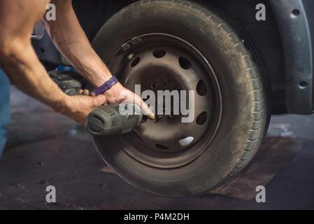 Close up of mechanic changing wheel with electric wrench. Stock Photo