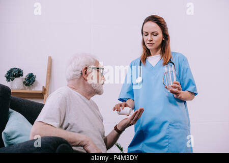 Nurse standing by senior man taking medications Stock Photo