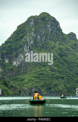 Tourists on wooden row boats and limestone (karst) mounds, Vung Vieng fishing village, Ha Long Bay, Bai Tu Long Sector, near Ha Long, Vietnam Stock Photo