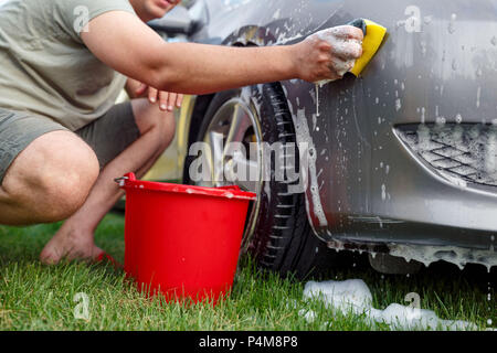 Sponge and bucket -Young man washing his car