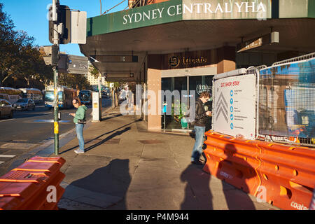 Entrance to the Sydney Central Youth Hostel Association with two people nearby using their mobile phones, Rawson Place, Haymarket, Sydney, Australia Stock Photo