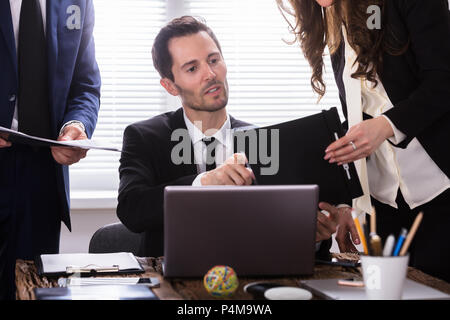 Young Businessman Looking At Document Shown By Partner Stock Photo
