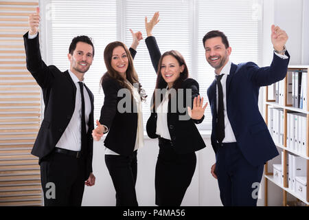 Portrait Of An Excited Young Businesspeople Raising Their Arms Stock Photo