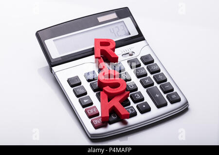 Elevated View Of Risk Word On Calculator Over White Background Stock Photo