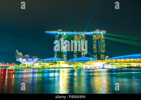 Singapore - April 27, 2018: iconic Marina Bay Sands with colored lights during laser show on Singapore harbor. Night scenes colorful waterfront. Popular tourist attraction in Marina Bay area. Stock Photo