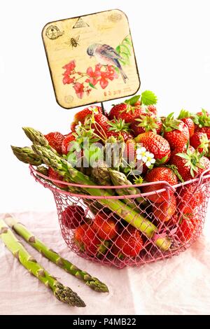 Strawberries and green asparagus in a wire basket with an old-fashioned sign Stock Photo