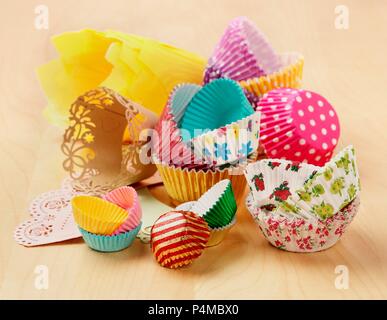 Various types and colours of cupcake and muffin cases on a wooden surface Stock Photo