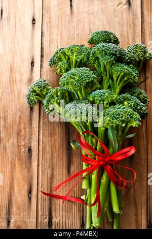 Broccolini with a red ribbon on a wooden surface Stock Photo