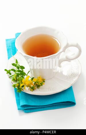 A cup of St. John's Wort tea and flowering St. John's Wort Stock Photo