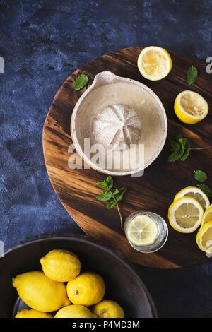 Lemon juicer, mint and fresh lemons on chopping board Stock Photo