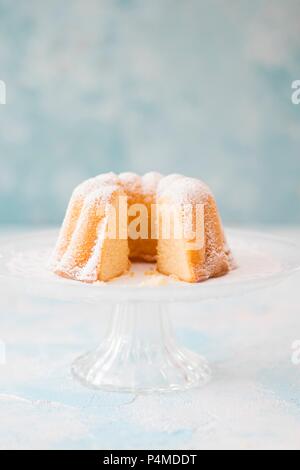 Lemon Bundt cake coated in icing sugar on a cake stand Stock Photo