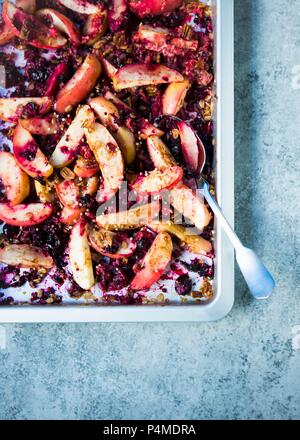 Slices of apples baked with fresh berries, oats, quinoa and pecan nuts on a baking tray Stock Photo