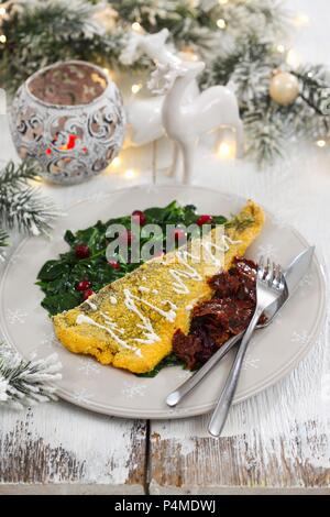 Fish fillet in polenta with spinach and dried tomatoes Stock Photo