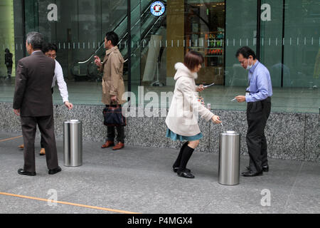 Japanese people smoke cigarettes in a special  smoking area on the street of Tokyo, Japan – jan, 24, 2011. Stock Photo