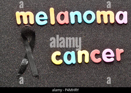 Melanoma awareness ribbon on black color background. Mourning and ...