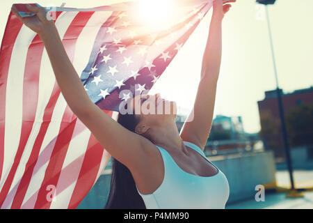 Happy young woman holding USA flag in air over head Stock Photo