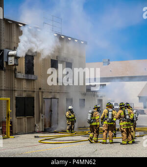 Firefighters in full turnout gear standing outside a burn building for training. Stock Photo