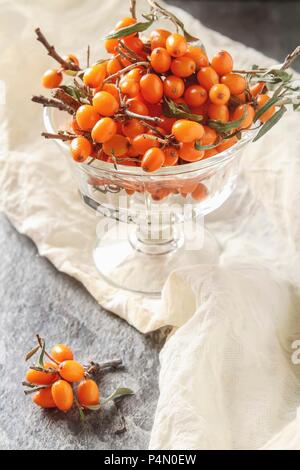 Fresh sea buckthorn berries with twigs in a glass bowl Stock Photo