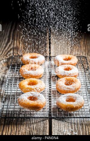 Freshly baked doughnuts being dusted with icing sugar Stock Photo