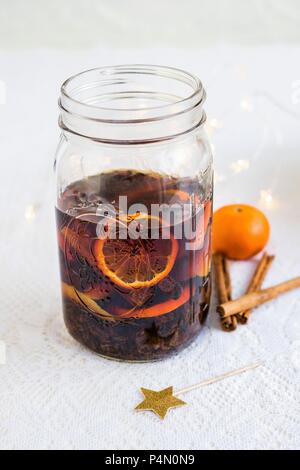 Homemade rum punch with clementines, raisins, cinnamon and lemon zest in a glass jar Stock Photo
