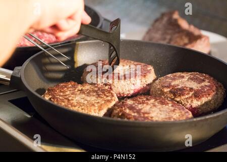 Burgers being fried in a pan Stock Photo