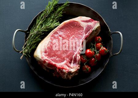 Côte de bœuf in a pan with cherry tomatoes and rosemary Stock Photo