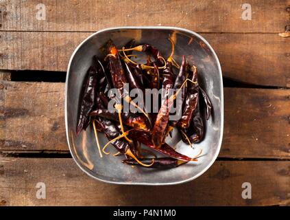 Dried Red Peppers in a Pewter Bowl on Wood Stock Photo