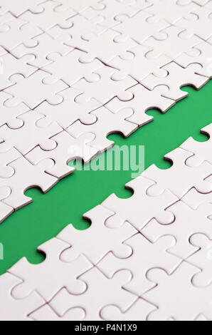 The green path is laid on the platform of a white folded jigsaw puzzle. Texture image with copy space for text Stock Photo