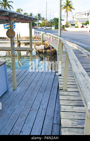 Old wooden walkway and dock along the coastline of Marsh Harbour, Bahamas downtown on sunny day, no traffic on street. Stock Photo