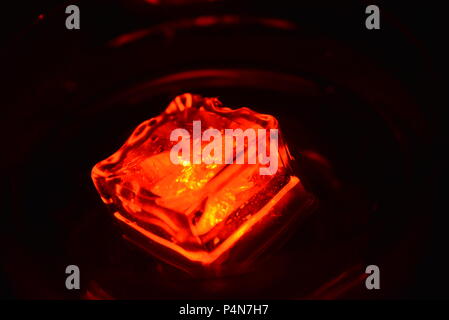 Beautiful, stylish photo of parties, celebrations, one glass champagne glass with glowing plastic ice cubes in drinks that glow red light. Stock Photo
