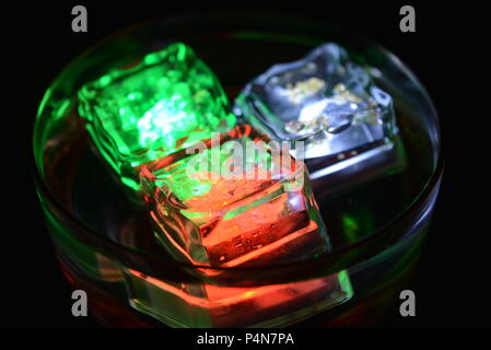 Beautiful, stylish photo of parties, celebrations, one glass champagne glass with glowing plastic ice cubes in drinks that glow with green, red, white Stock Photo