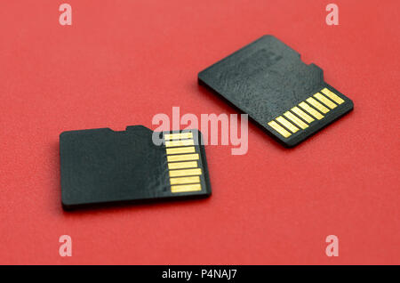 Two small micro SD memory cards lie on a red background. A small and compact data and information store . Stock Photo