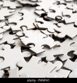 Close-up of a pile of uncompleted elements of a white puzzle. A huge number of rectangular pieces from one large white mosaic Stock Photo