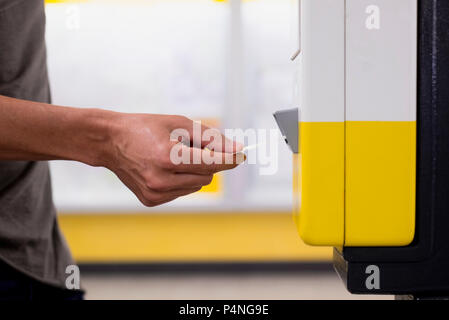 closeup of a young caucasian man validating his train or subway ticket in a machine Stock Photo