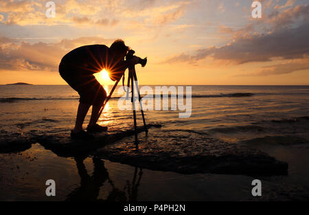Nature photographer working at sunset to create nature photographs at Byrums Raukar, Öland, Sweden Stock Photo
