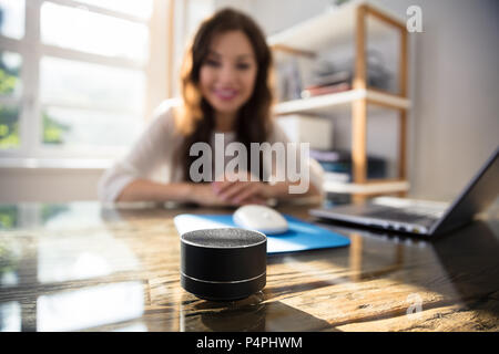 Close-up Of Wireless Speaker In Front Of Businesswoman Listening To Music Stock Photo