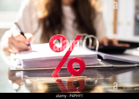 Close-up Of Percentage Symbol In Front Of Businessperson Working On Document Stock Photo