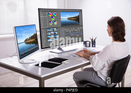 Young Female Editor Editing Video On Computer In Office Stock Photo